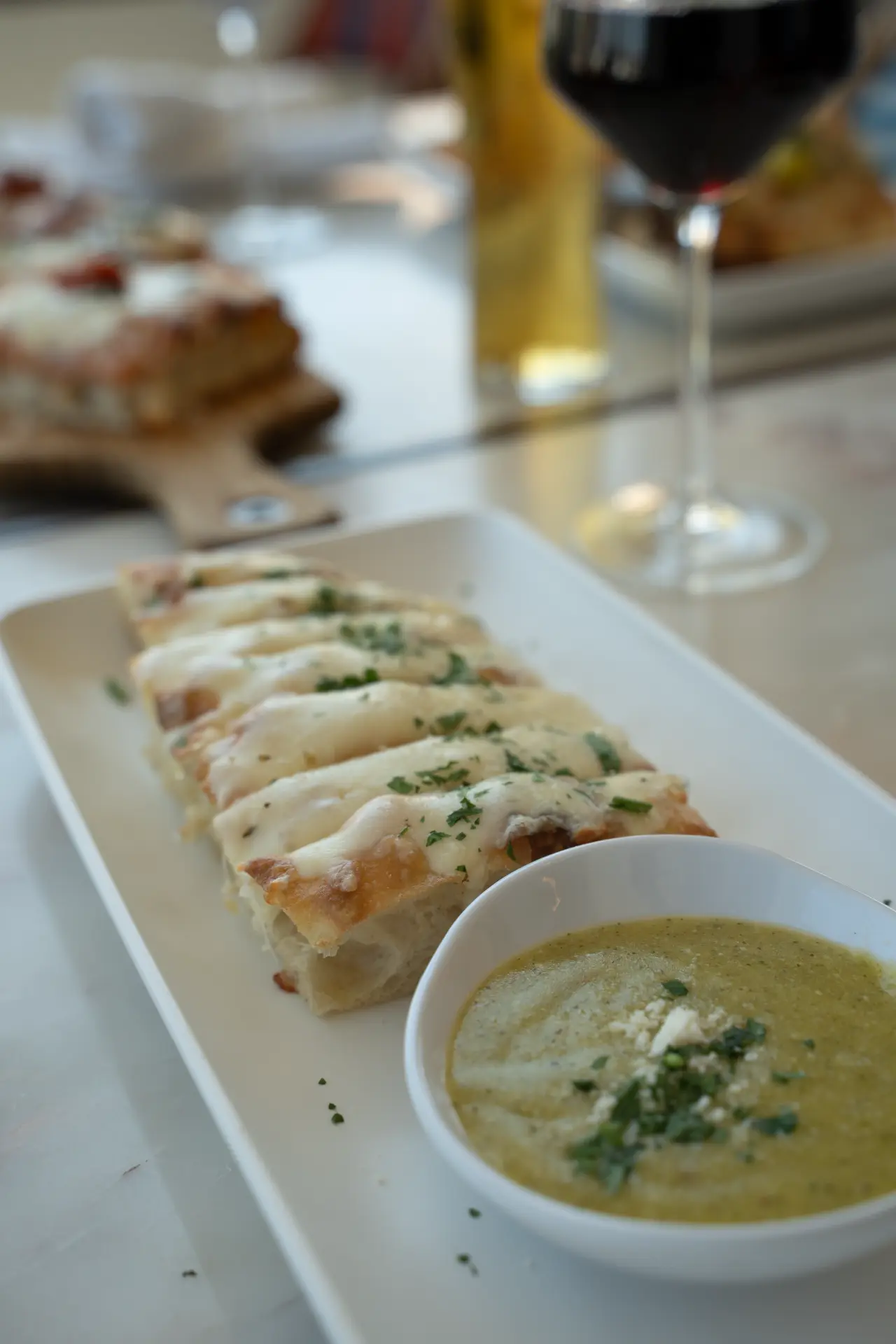 Cheesy flatbread with dipping sauce and red wine